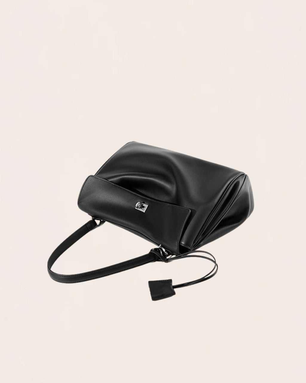 The black leather flap bag lying flat with the flap folded open and the strap loose