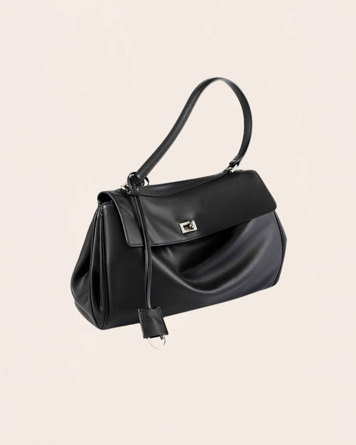 The black leather flap bag at three quarters, top handle raised, leather tag hanging at the side