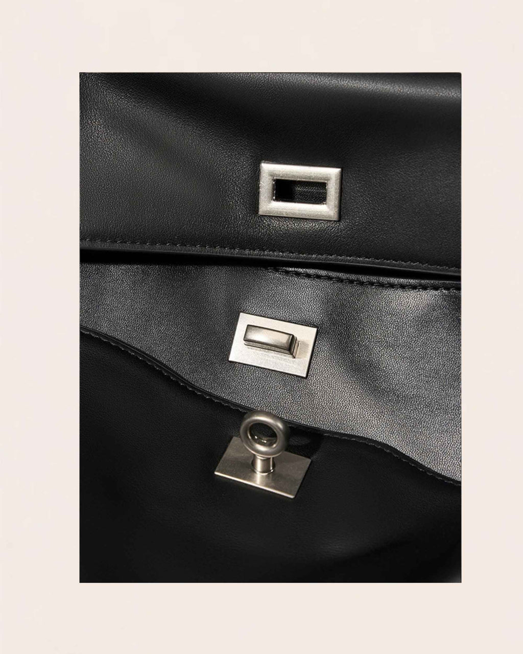 The two brushed silver turn locks, one on the outer flap and one on the panel beneath it