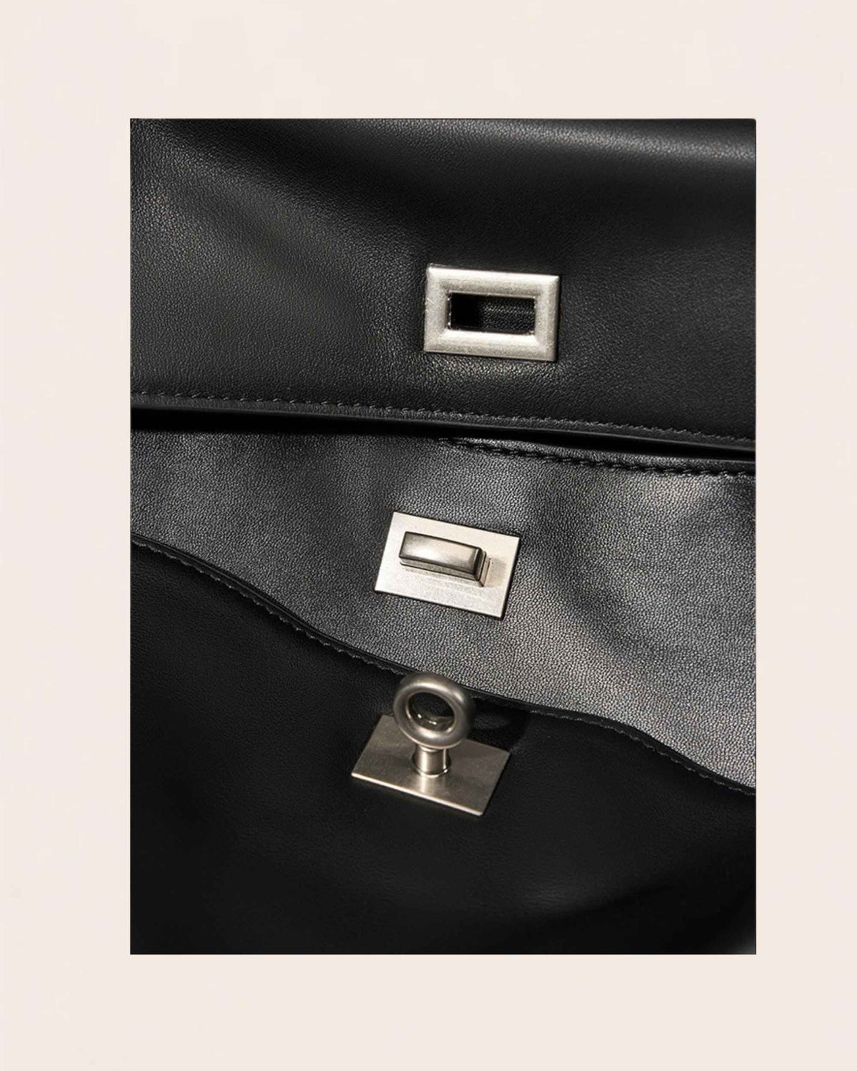 The two brushed silver turn locks, one on the outer flap and one on the panel beneath it